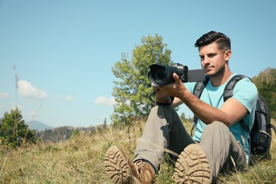 Photo of Professional photographer taking picture with modern camera in mountains. Space for text