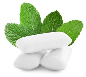 Menthol chewing gum pillows and mint leaves on white background