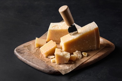 Delicious parmesan cheese with knife on black table