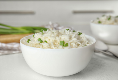 Photo of Bowl with tasty cooked rice on white table