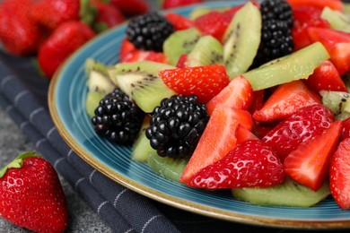 Photo of Plate of delicious fresh fruit salad on table, closeup