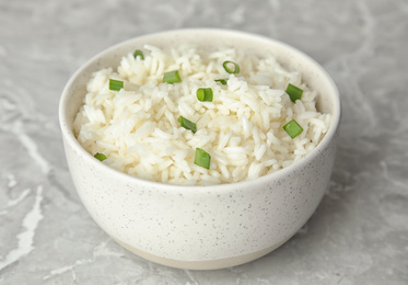 Photo of Bowl with tasty cooked rice on light grey marble table, closeup
