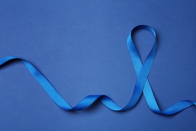 Photo of Blue ribbon on color background, top view. Colon cancer awareness concept