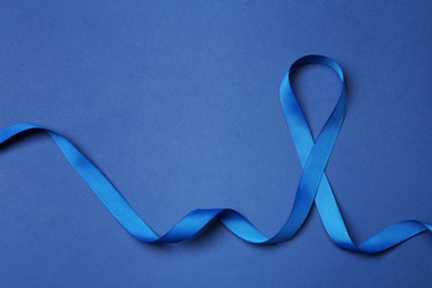 Blue ribbon on color background, top view. Colon cancer awareness concept