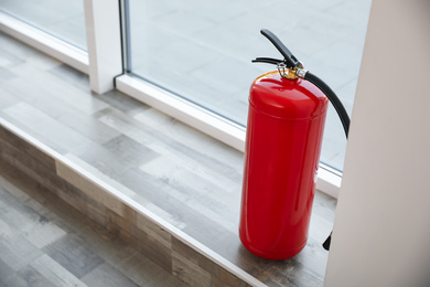 Fire extinguisher near window indoors. Space for text