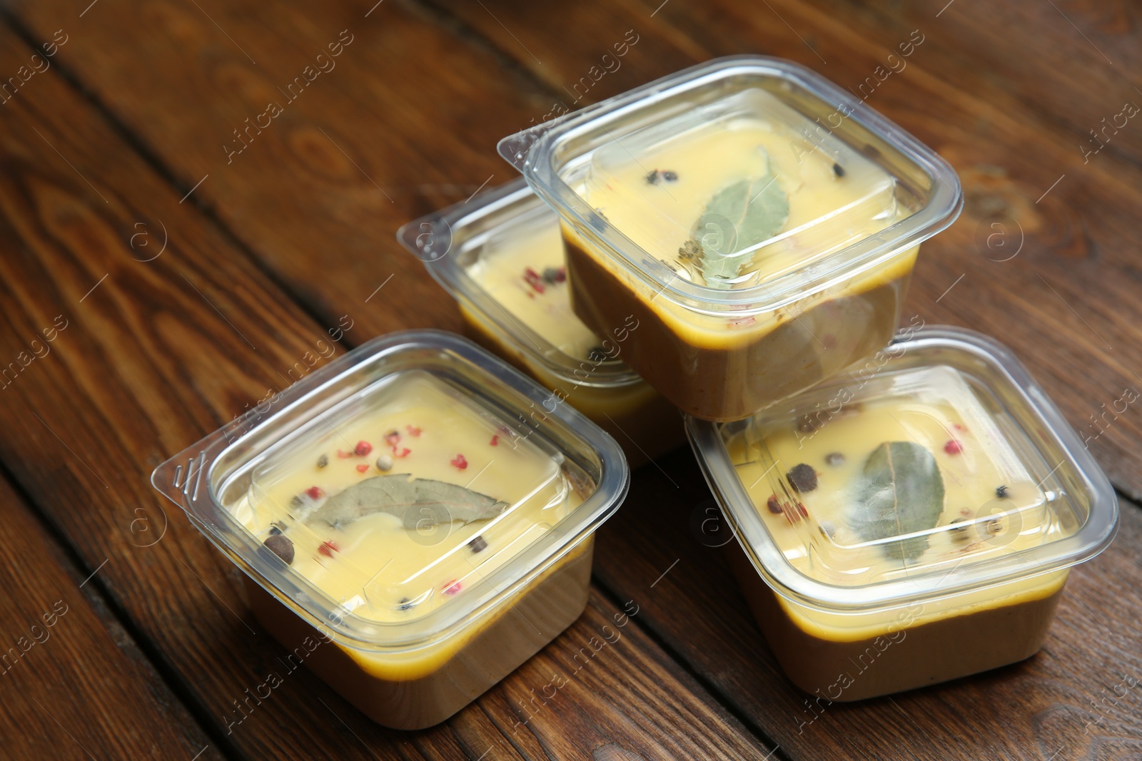 Photo of Delicious chicken liver pate in plastic containers on wooden table. Food delivery service