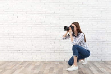 Photo of Professional photographer taking picture near white brick wall. Space for text