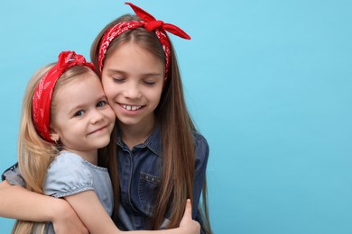 Photo of Cute little sisters on light blue background, space for text