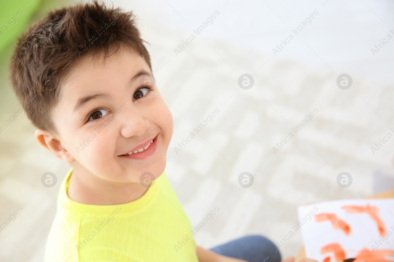 Photo of Cute little child painting in playing room, closeup