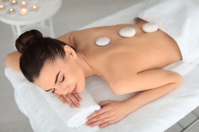 Young woman undergoing hot stone therapy in spa salon