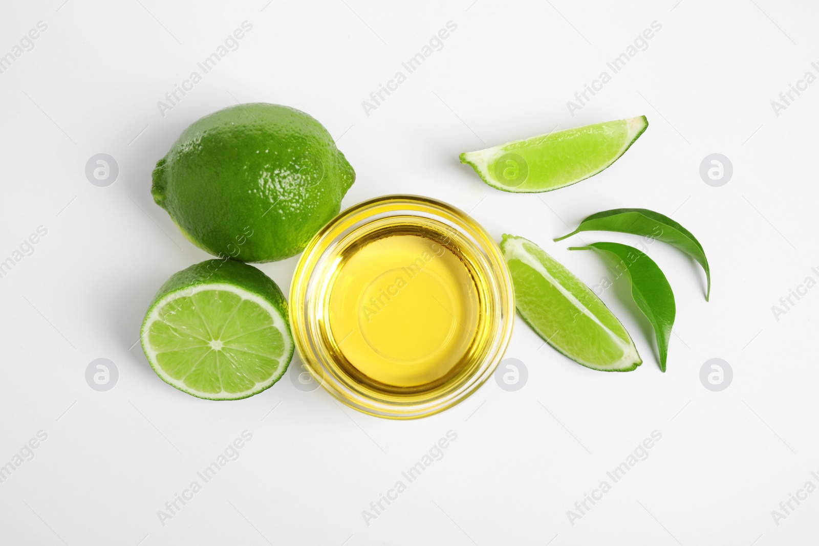 Photo of Lime essential oil in bowl and citrus fruits isolated on white, top view