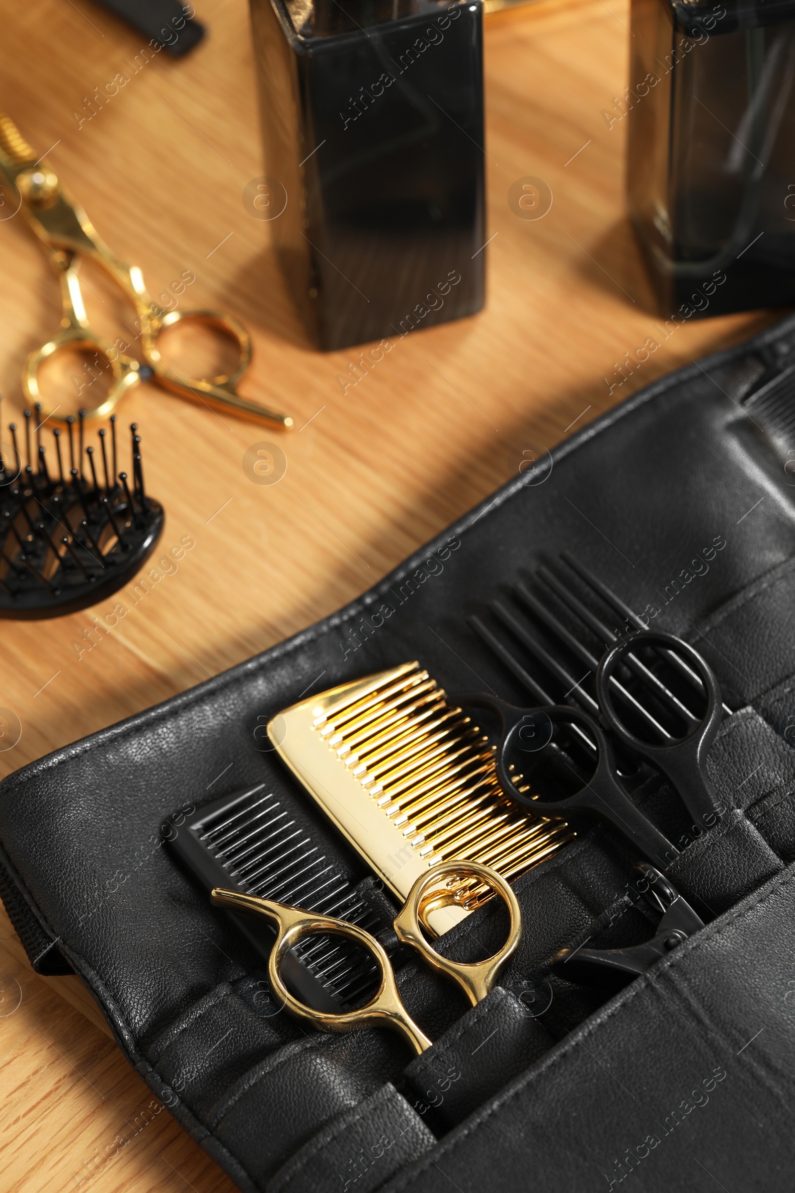 Photo of Hairdresser tools. Professional scissors and combs in leather organizer on wooden table, closeup