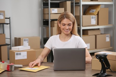 Photo of Seller with parcels and laptop in office. Online store