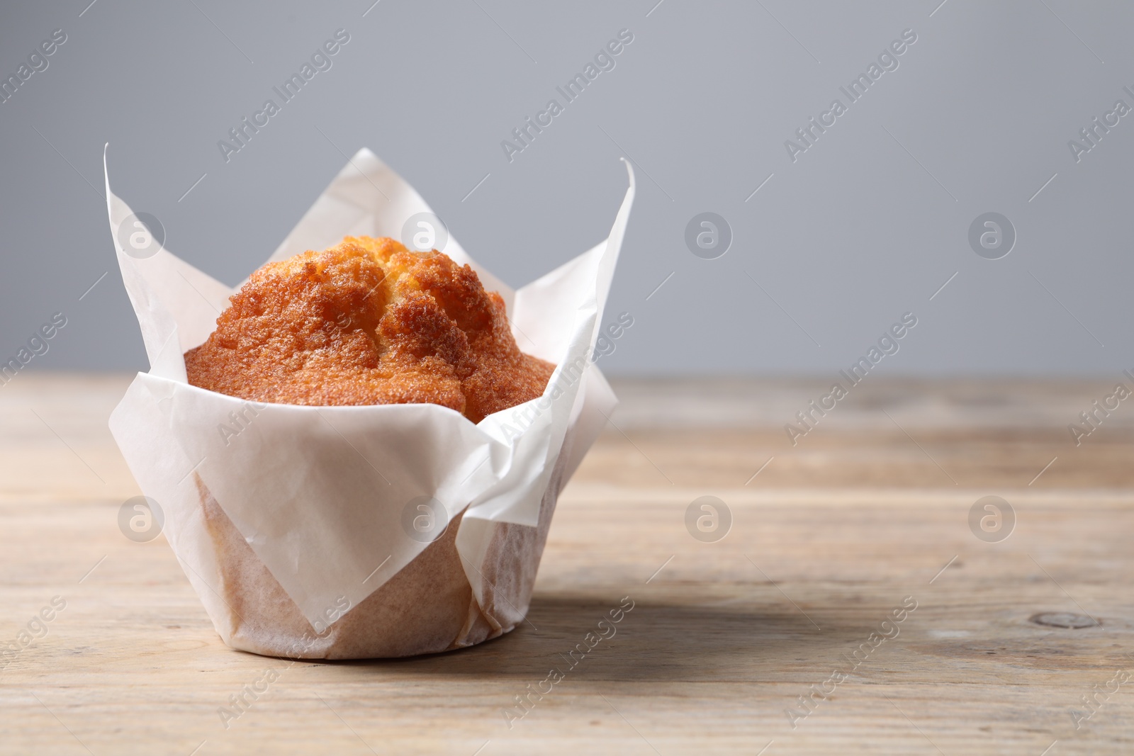 Photo of Delicious sweet muffins on wooden table against grey background, closeup. Space for text