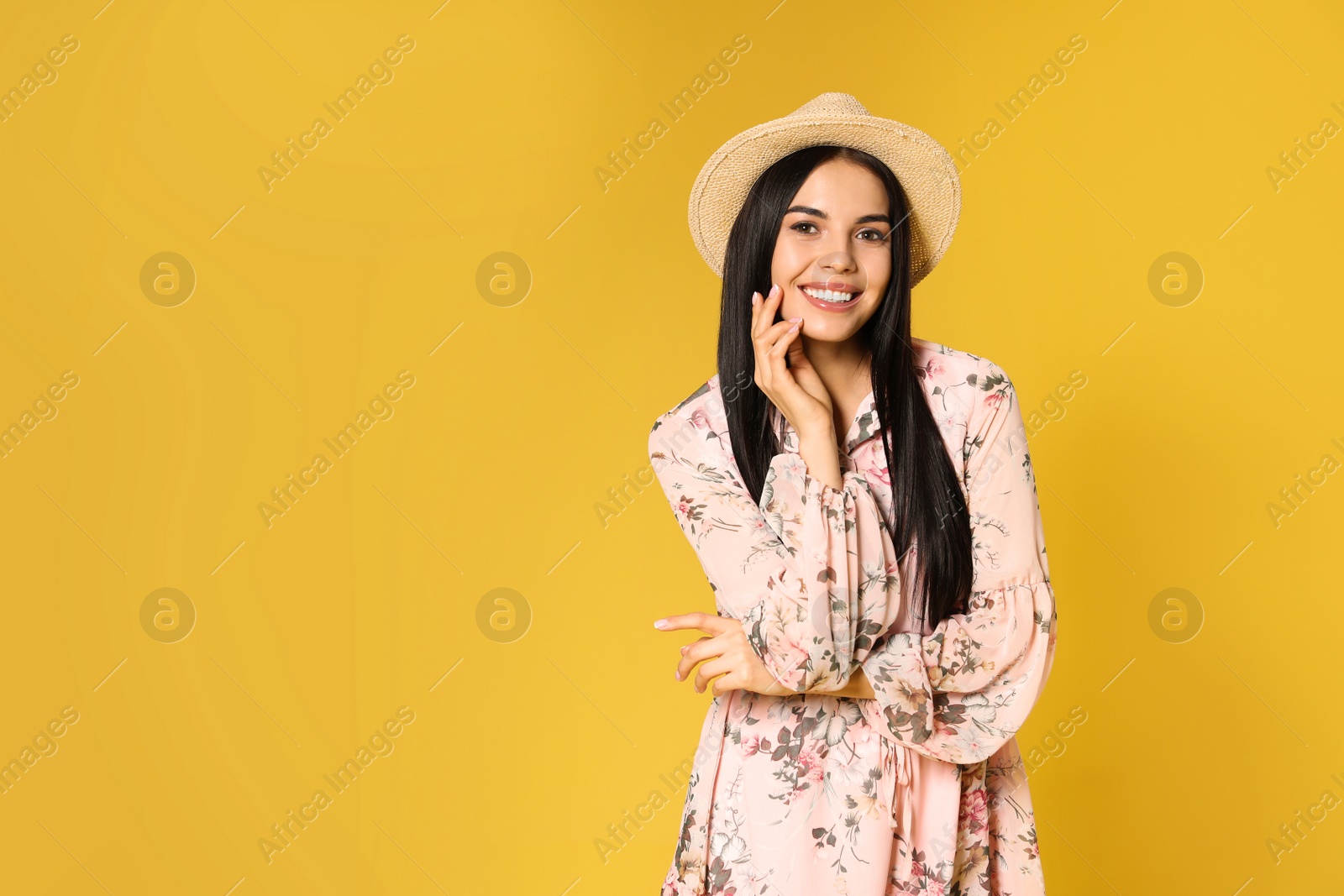 Photo of Young woman wearing floral print dress and straw hat on yellow background. Space for text