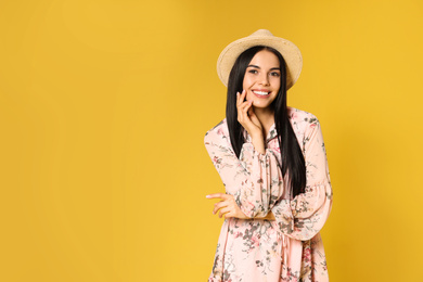 Photo of Young woman wearing floral print dress and straw hat on yellow background. Space for text