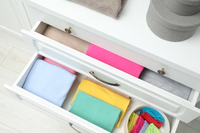 Photo of Chest of drawers with different folded clothes indoors, top view