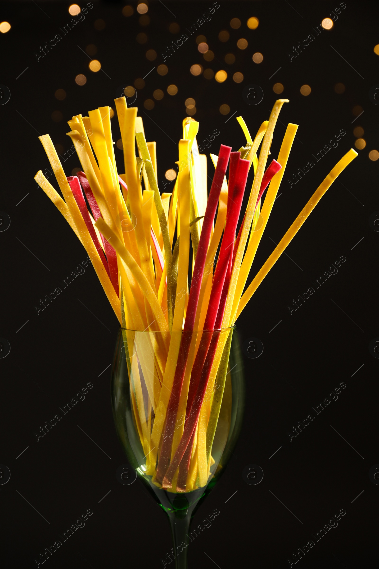 Photo of Uncooked noodles against blurred lights, closeup. Italian pasta