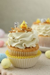 Tasty Easter cupcake with vanilla cream and candies on table