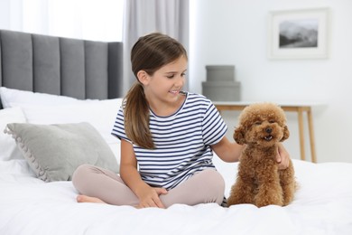 Little child and cute puppy on bed at home. Lovely pet