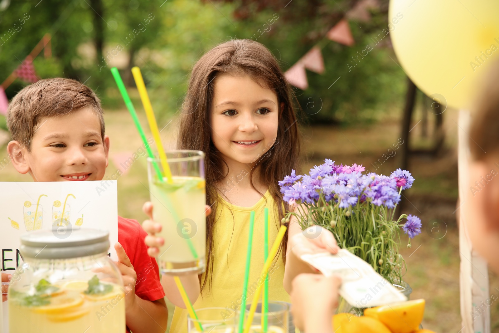 Photo of Little kids selling natural lemonade at stand in park