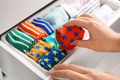 Photo of Woman putting color socks into open drawer, closeup