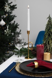 Photo of Festive place setting with beautiful dishware, candle and fabric napkin for Christmas dinner on white table