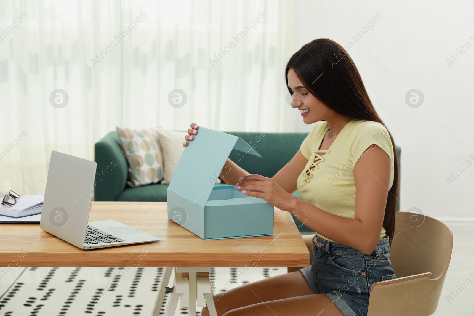 Photo of Happy young woman opening parcel at home. Internet shopping