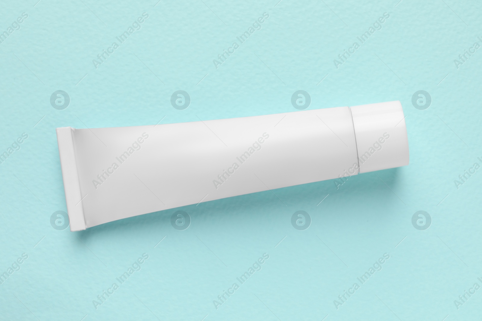 Photo of Tube of ointment on light blue background, top view. Space for text