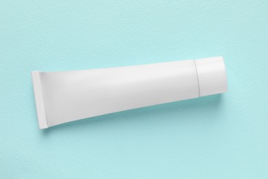 Photo of Tube of ointment on light blue background, top view. Space for text