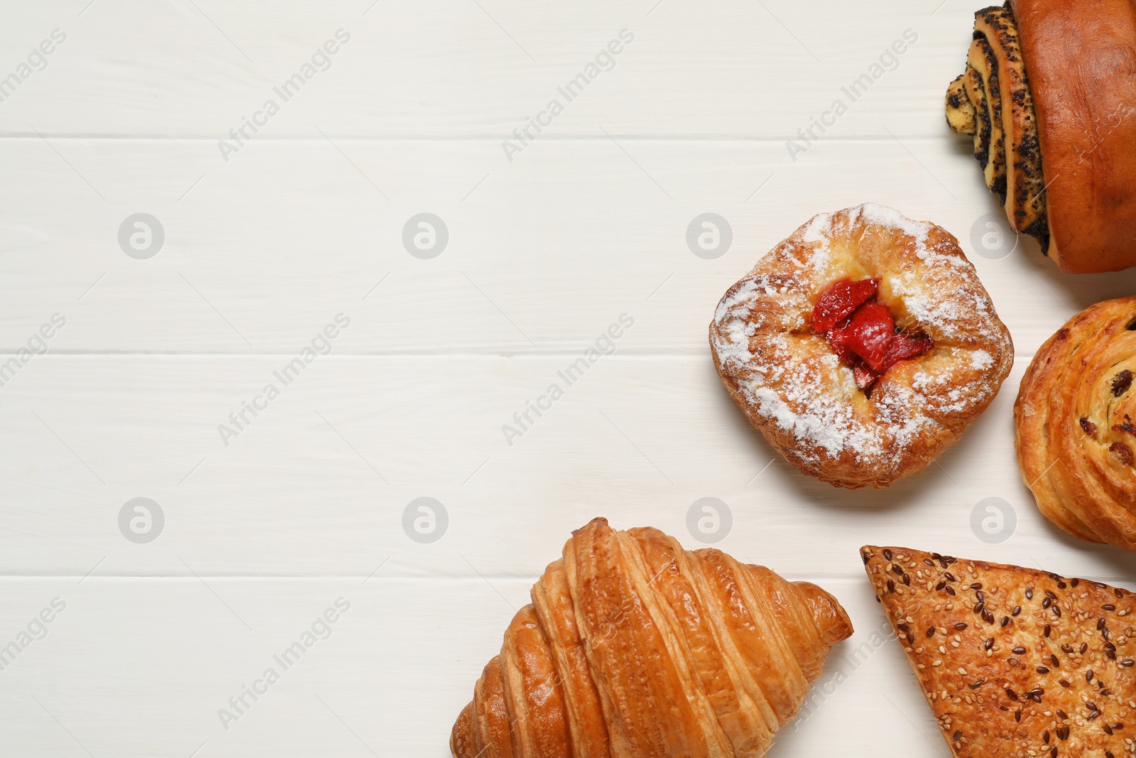 Photo of Different tasty freshly baked pastries on white wooden table, flat lay. Space for text