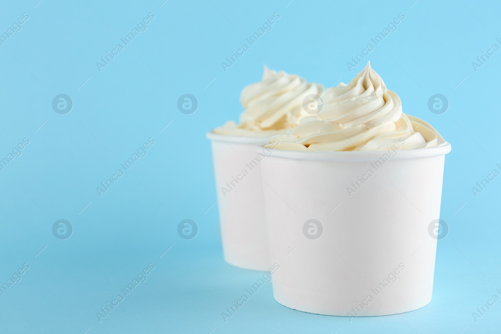 Photo of Cups with tasty frozen yogurt on blue background. Space for text