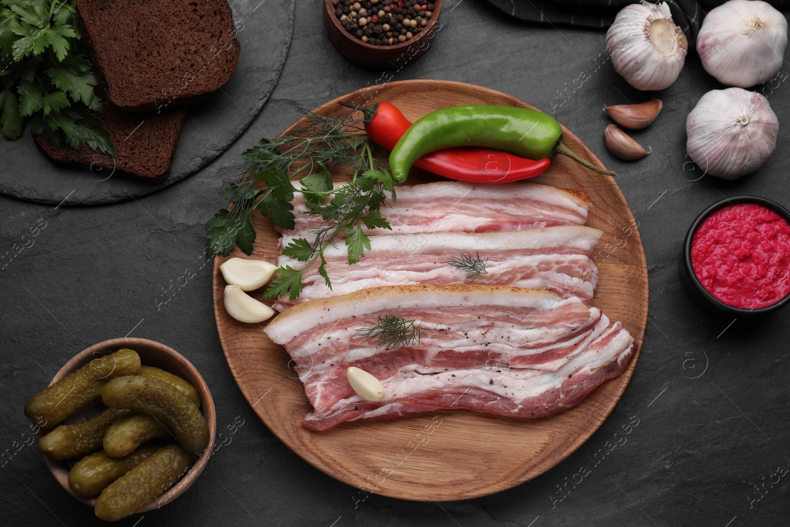 Photo of Flat lay composition with tasty pork fatback and ingredients on black table