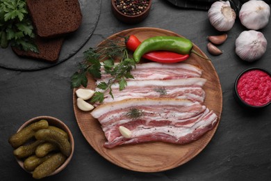 Flat lay composition with tasty pork fatback and ingredients on black table