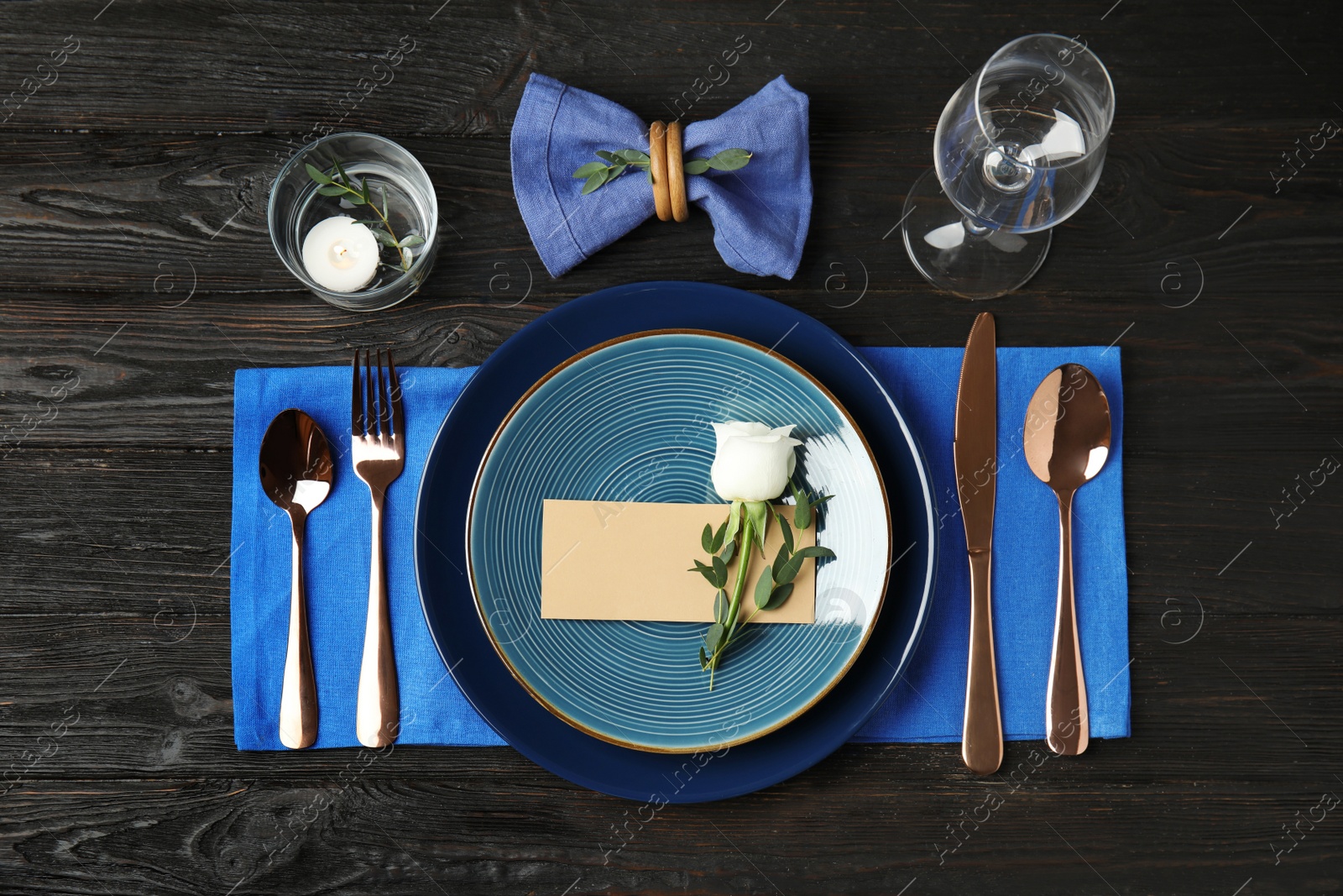 Photo of Elegant festive table setting with blank card on black wooden background, flat lay