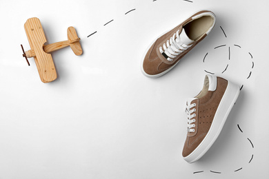 Stylish shoes and wooden toy plane on white background, top view
