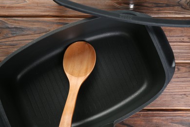 Black pot and spoon on wooden table, flat lay