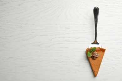 Piece of fresh homemade pumpkin pie on white wooden table, top view