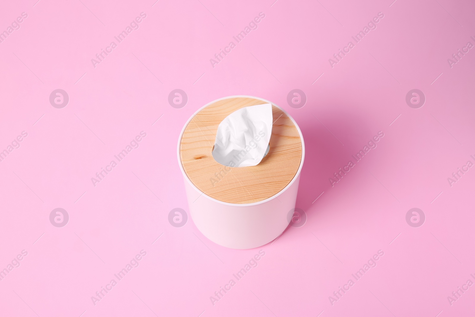 Photo of Holder with paper tissues on pink background