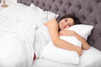 Beautiful woman lying on comfortable pillow in bed at home