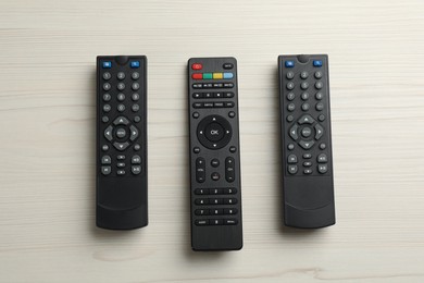 Photo of Modern tv remote controls on white wooden table, flat lay