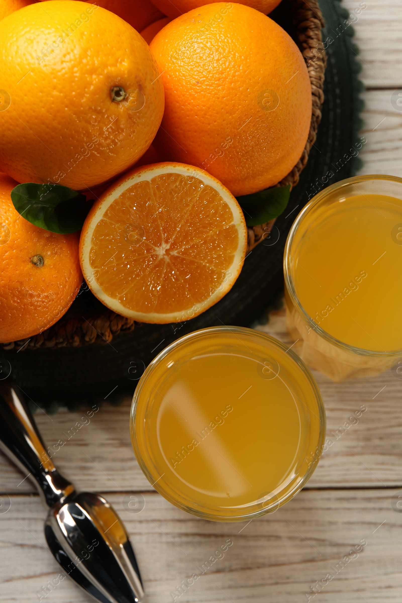 Photo of Many ripe juicy oranges, squeezer and fresh juice on white wooden table, flat lay