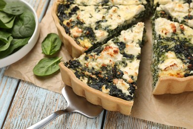 Taking piece of delicious homemade spinach quiche on table, closeup