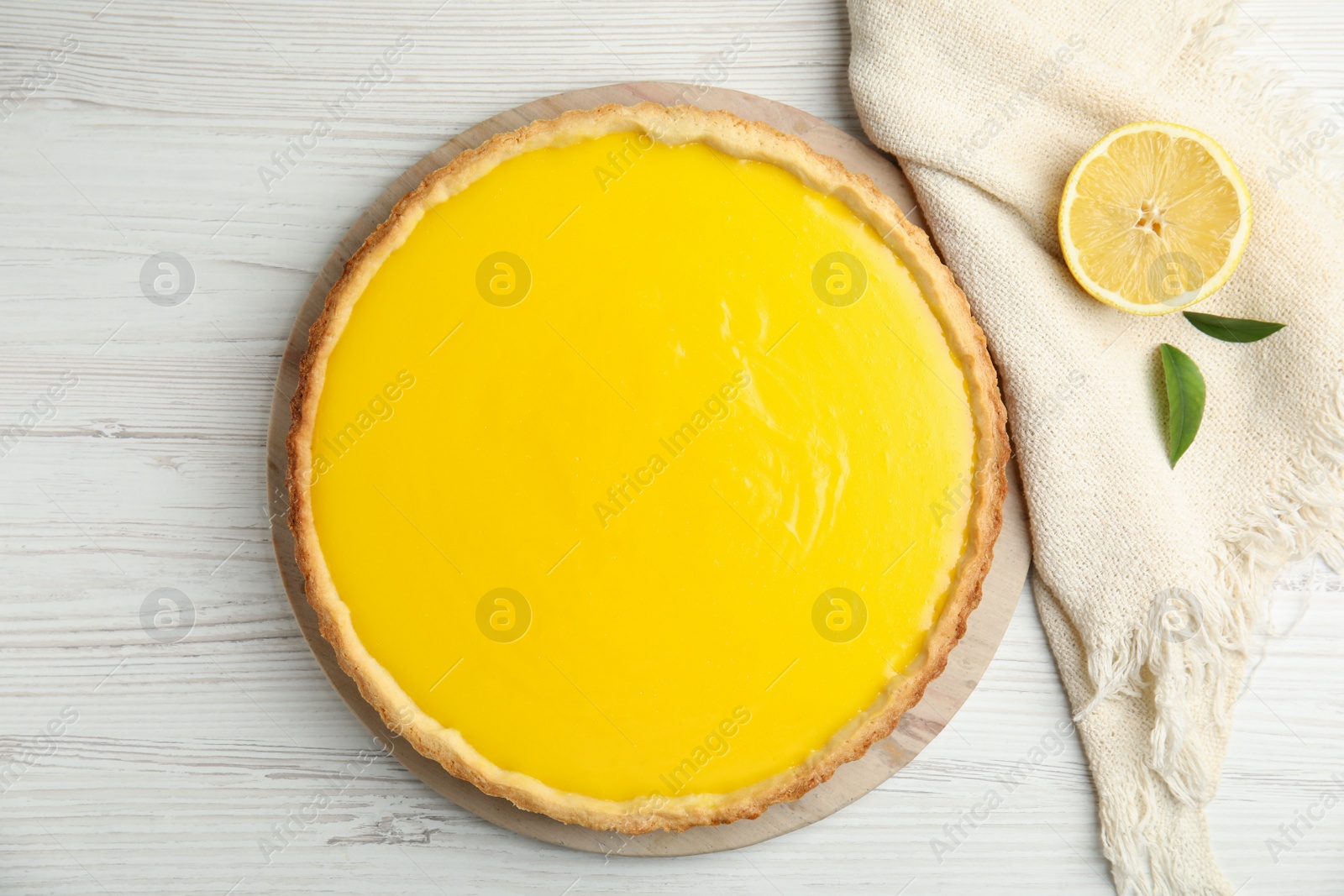 Photo of Delicious homemade lemon pie and half of fruit on white wooden table, flat lay