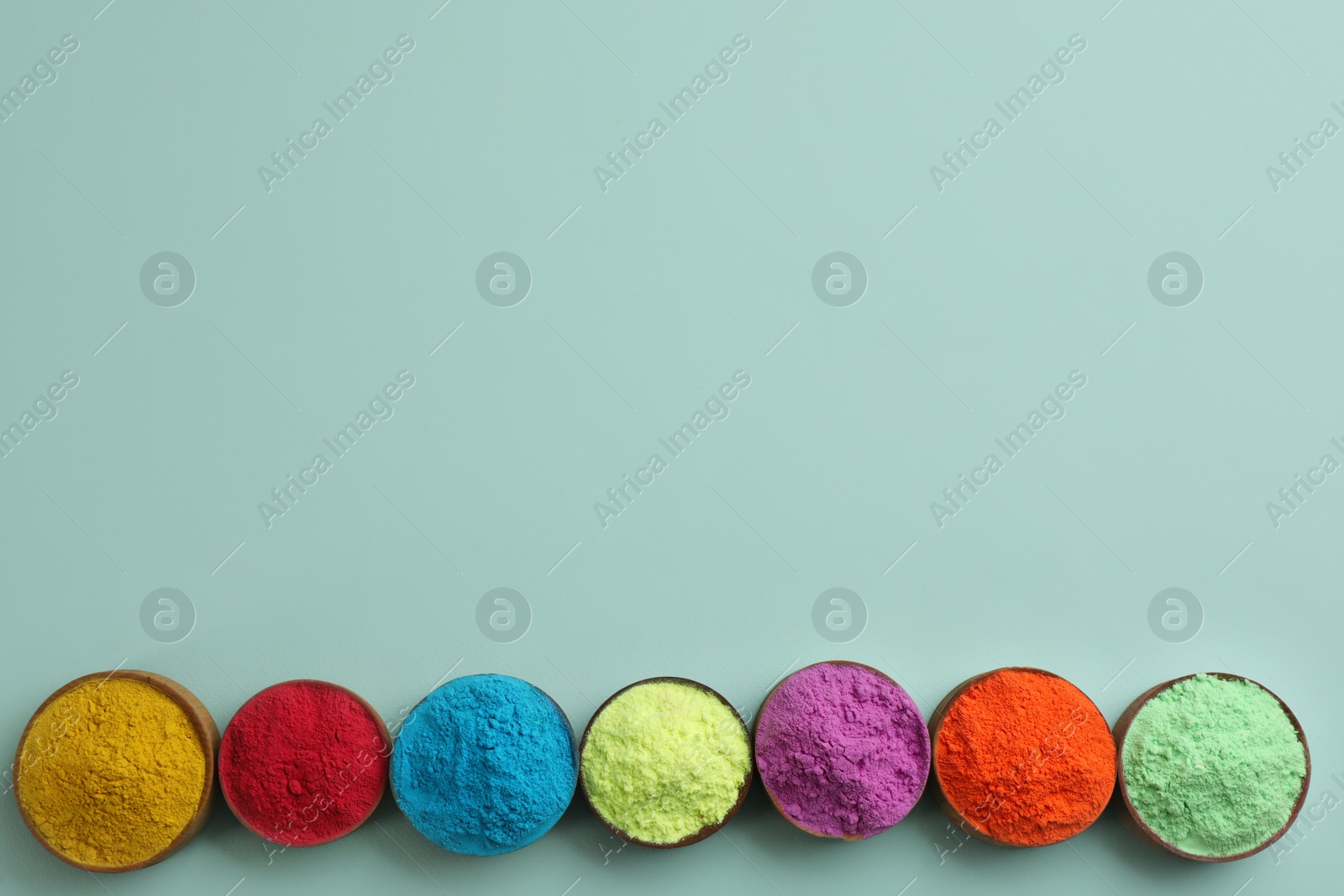 Photo of Colorful powders in bowls on light background, flat lay with space for text. Holi festival celebration