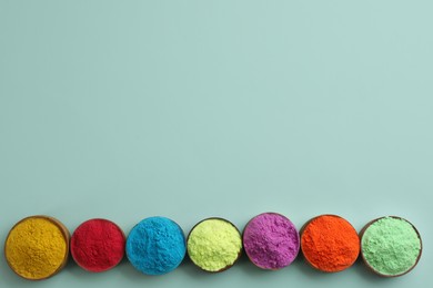 Photo of Colorful powders in bowls on light background, flat lay with space for text. Holi festival celebration