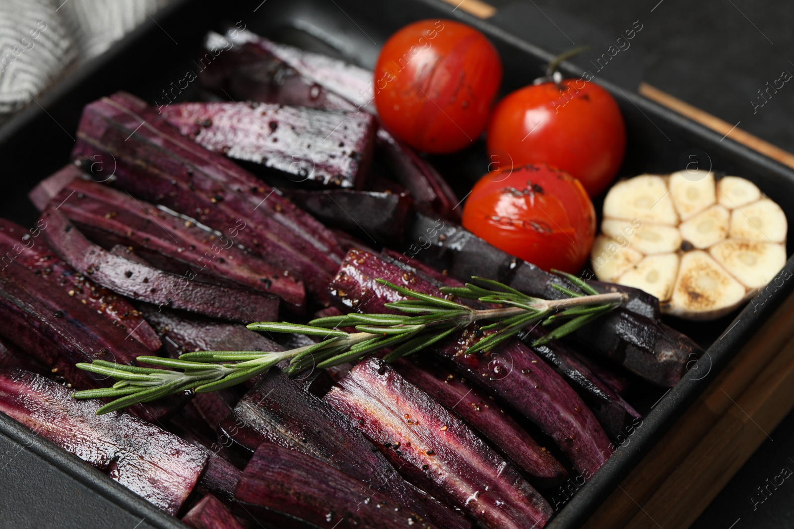 Photo of Cut raw carrot with vegetables and rosemary in baking dish, closeup