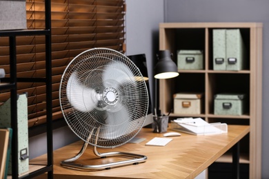 Photo of Modern electric fan on table in office