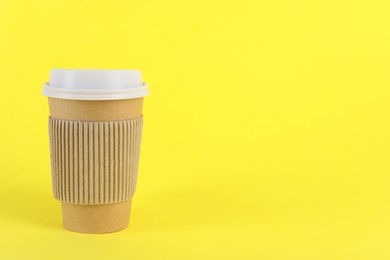 Paper cup with plastic lid on yellow background, space for text. Coffee to go