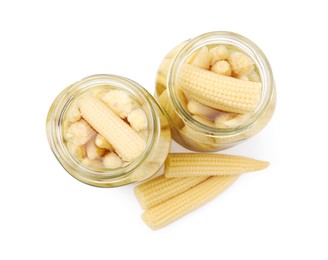 Photo of Jars and pickled baby corn isolated on white, top view